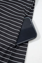 Black striped mini dress with ruffle sleeves and a smartphone tucked into the pocket.
