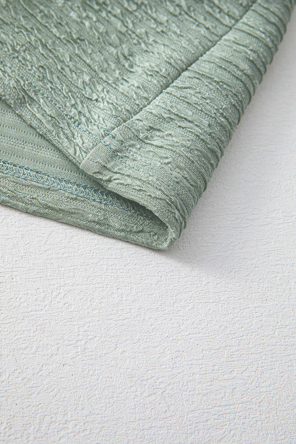 Close-up of the crinkle-textured fabric of the Minted Moments Dress in soft sage green.