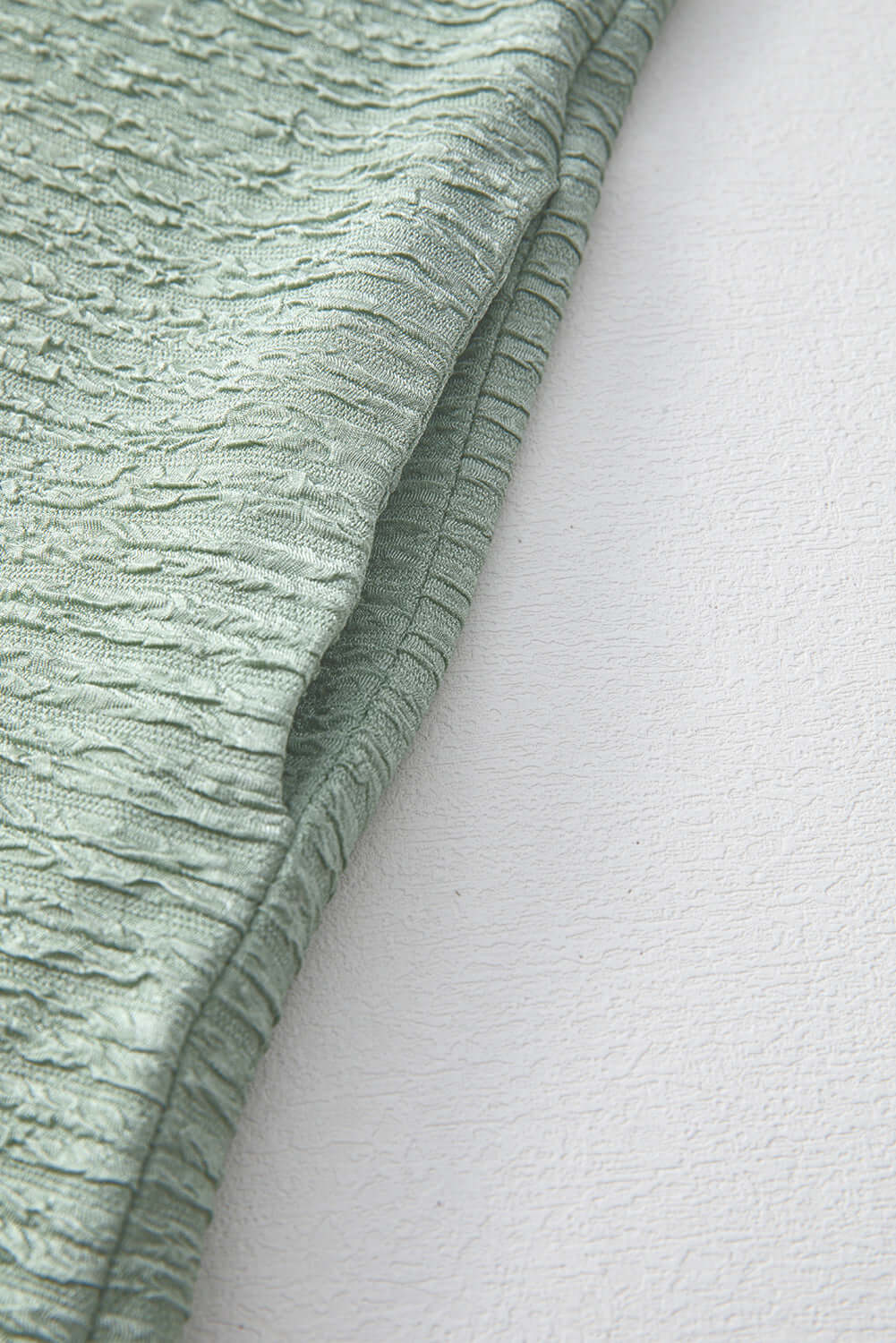 Close-up of the crinkle-textured fabric of the Minted Moments Dress in soft sage green.