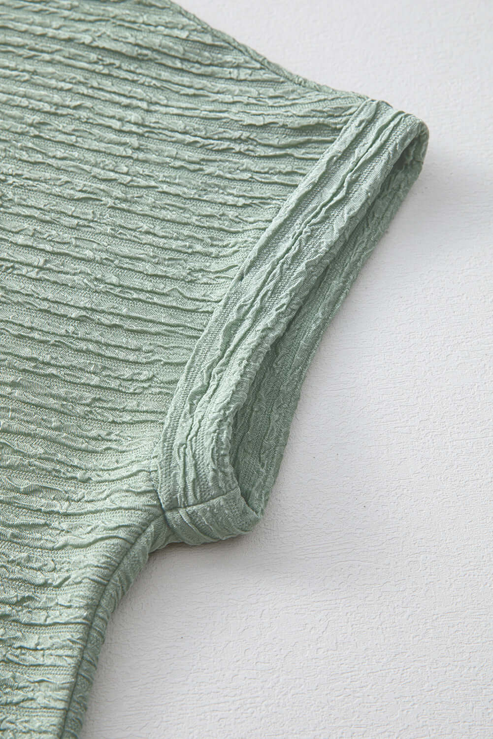 Close-up of the crinkle-textured sleeve of the Minted Moment Dress in sage green.