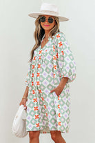 Model wearing a mint mosaic dress with green floral pattern, V-neck, and 3/4 puff sleeves.
