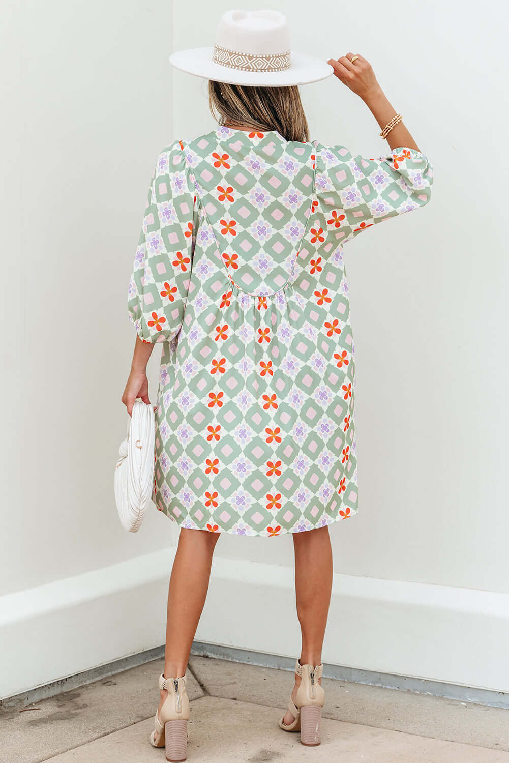 Woman in a mint mosaic dress with a notched V-neck and 3/4 puff sleeves, showcasing a geometric floral pattern.