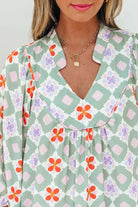 Close-up of woman in Mint Mosaic Dress featuring green geometric floral pattern and notched V-neck design.