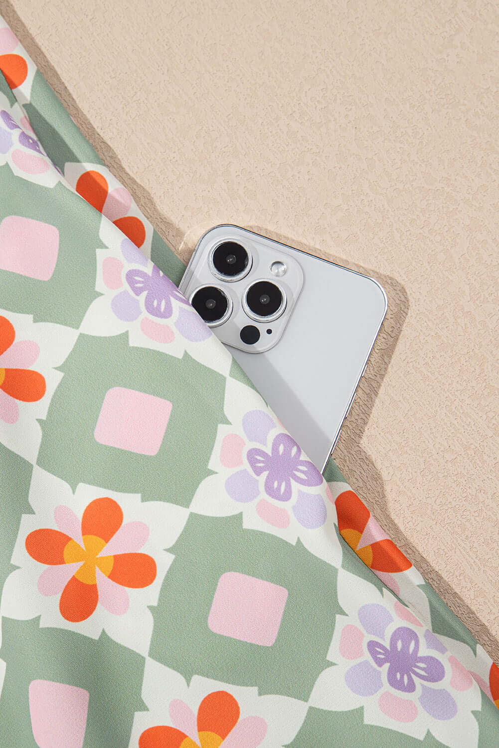 Close-up of mint geometric floral fabric featuring an iPhone, showcasing stylish design and vibrant colors.