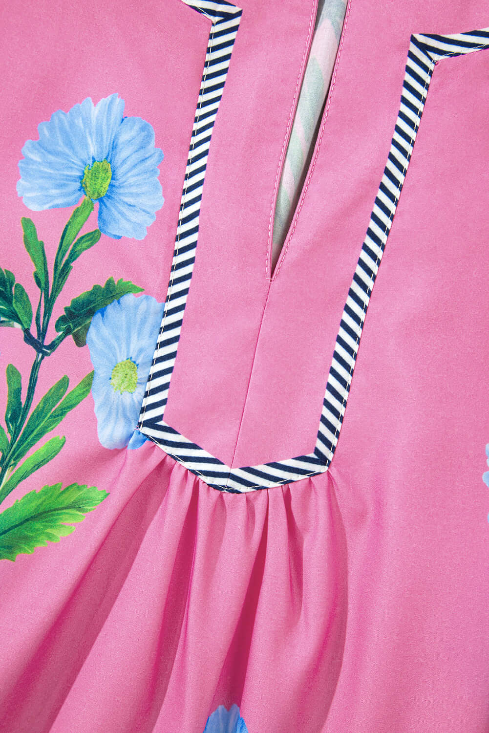 Close-up of Coastal Kiss Dress in magenta with floral print and striped trim, showcasing lightweight fabric and playful design.