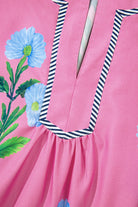 Close-up of Coastal Kiss Dress in magenta with floral print and striped trim, showcasing lightweight fabric and playful design.