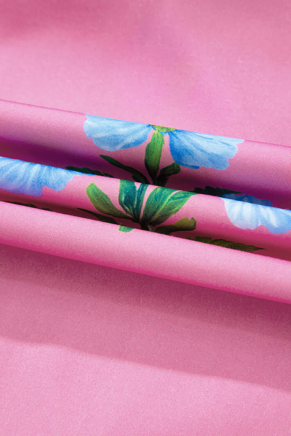Close-up of lightweight magenta fabric with vibrant blue floral pattern, ideal for summer dresses.