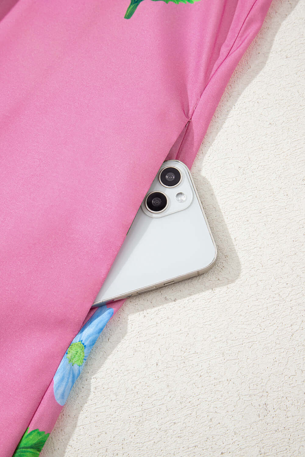 Magenta floral Coastal Kiss Dress with a smartphone tucked into the pocket, perfect for sunny days.