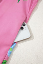 Magenta floral Coastal Kiss Dress with a smartphone tucked into the pocket, perfect for sunny days.