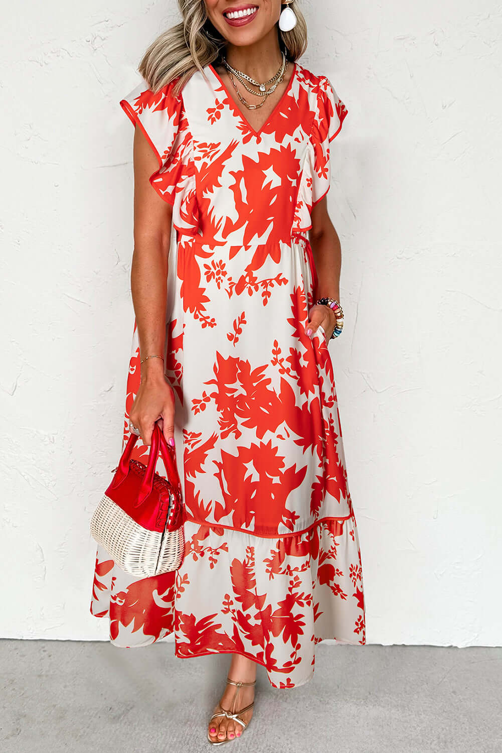 Woman in a red floral Salsa Garden Dress with flutter sleeves, perfect for summer events and stylish outings.