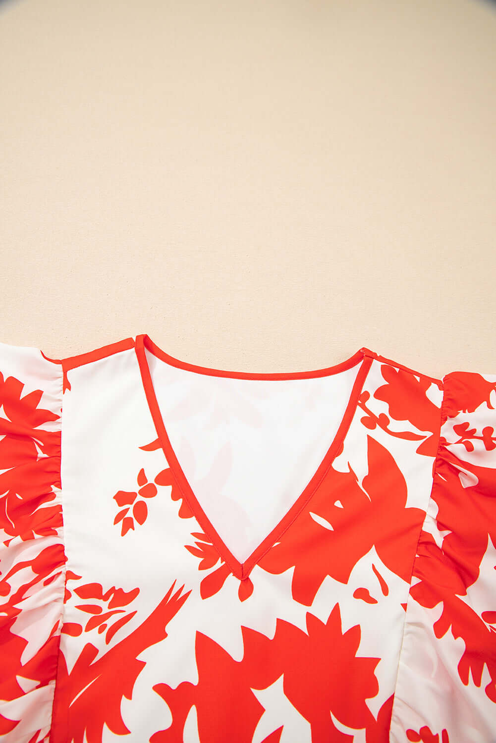Close-up of Salsa Garden Dress with red floral print and flutter sleeves on ivory background.