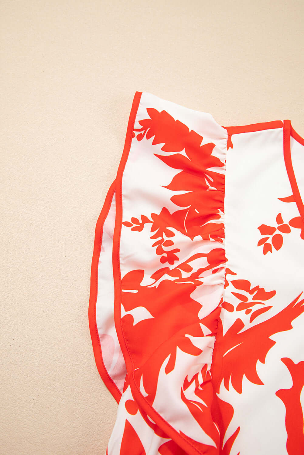 Close-up of the Salsa Garden Dress showcasing vibrant red floral print on ivory fabric with flutter sleeves.