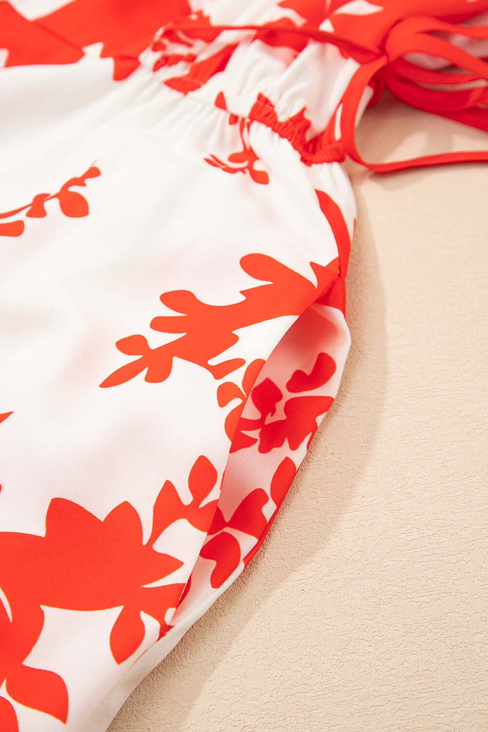 Close-up of Salsa Garden Dress featuring vibrant red floral print on ivory fabric, showcasing flowy design and feminine flutter sleeves.