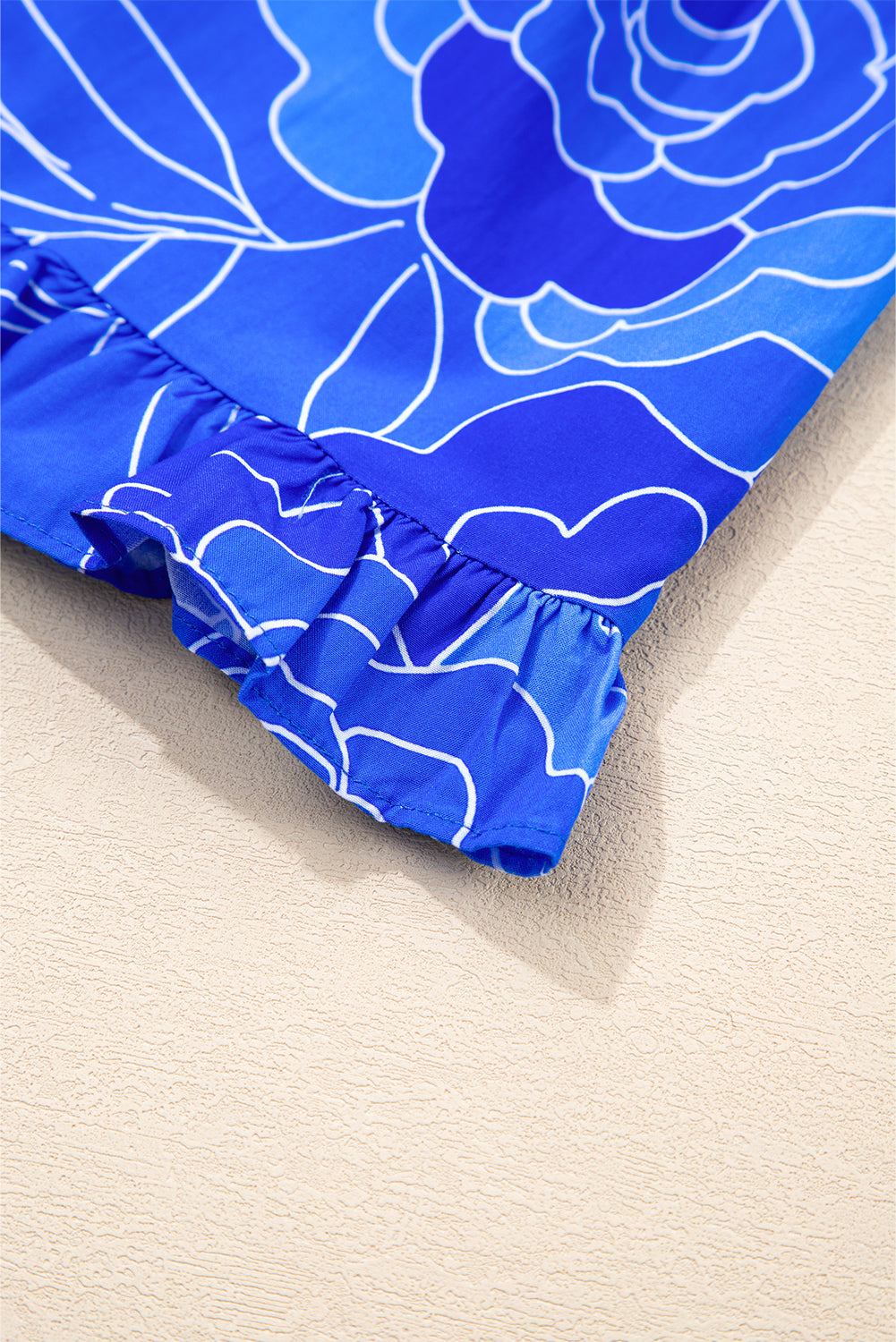 Close-up of the ruffled hem of the Blue Crush Dress showcasing vibrant blue floral design.