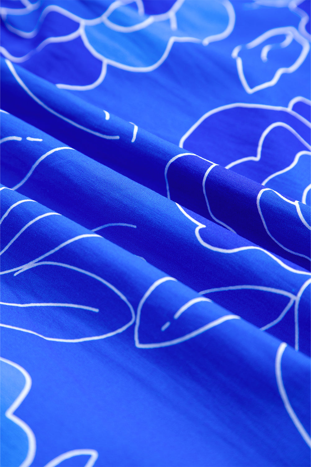 Close-up of vibrant cobalt fabric with white floral print, showcasing the design of the Blue Crush Dress.