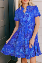 Blue Crush Dress featuring a vibrant floral print, short sleeves, and a tiered skirt for a playful, feminine look.