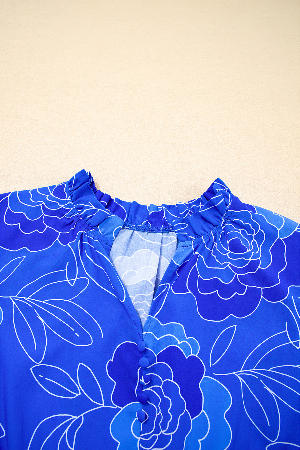 Close-up of the Blue Crush Dress featuring a floral design, V-neckline, and ruffled collar in vibrant cobalt blue.