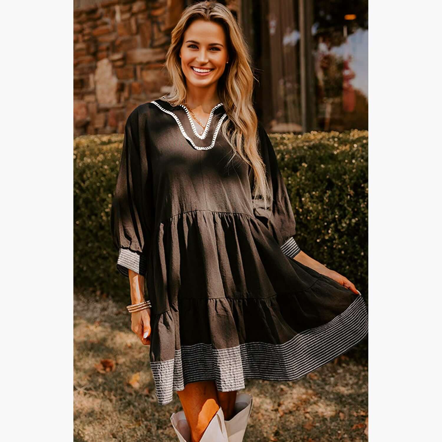 Model wearing Midnight Melody black babydoll dress with contrast stitching and tiered design, perfect for any occasion.
