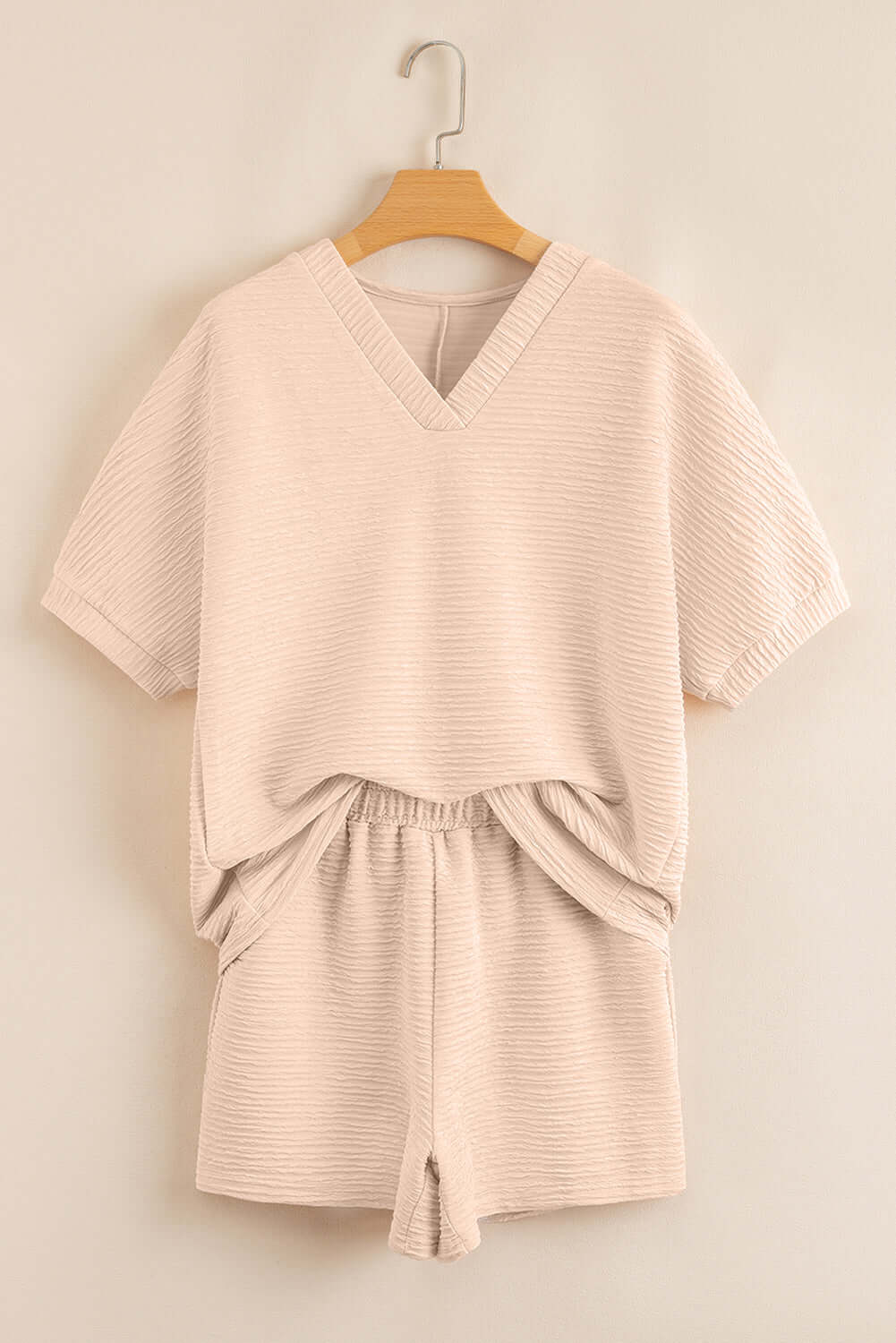 Textured pink two-piece set featuring a V-neck top and elastic waistband shorts, perfect for casual outings.