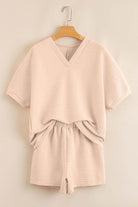 Textured pink two-piece set featuring a V-neck top and elastic waistband shorts, perfect for casual outings.