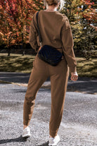 Model wearing Elemental Energy Set, a cozy cocoa high low sweatshirt and lounge pants, paired with a stylish black bag.