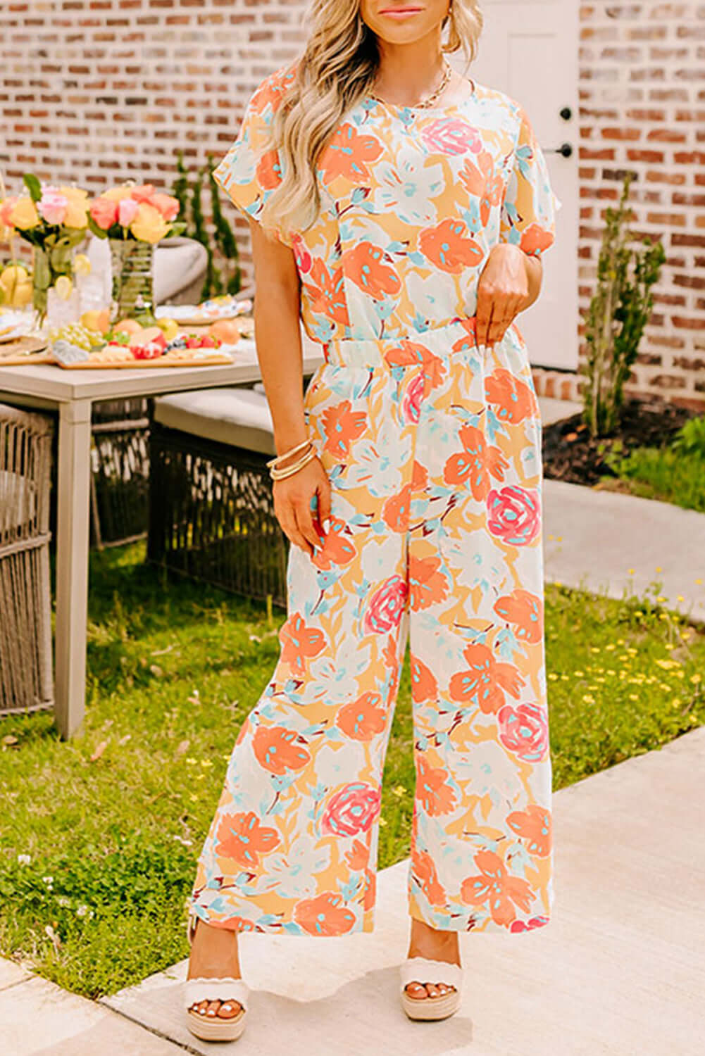 Stylish woman in Sunset Stroll Pants Set, featuring vibrant floral print top and wide-leg pants, perfect for a summer outing.