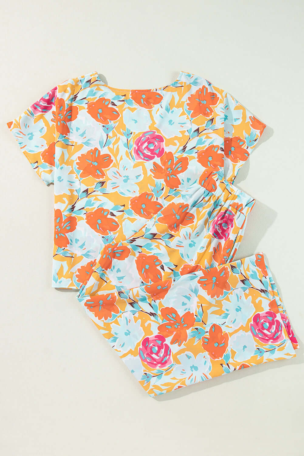Sunset Stroll Pants Set featuring a vibrant floral print with tangerine, coral, pink, and mint colors on a short-sleeve top and pants.