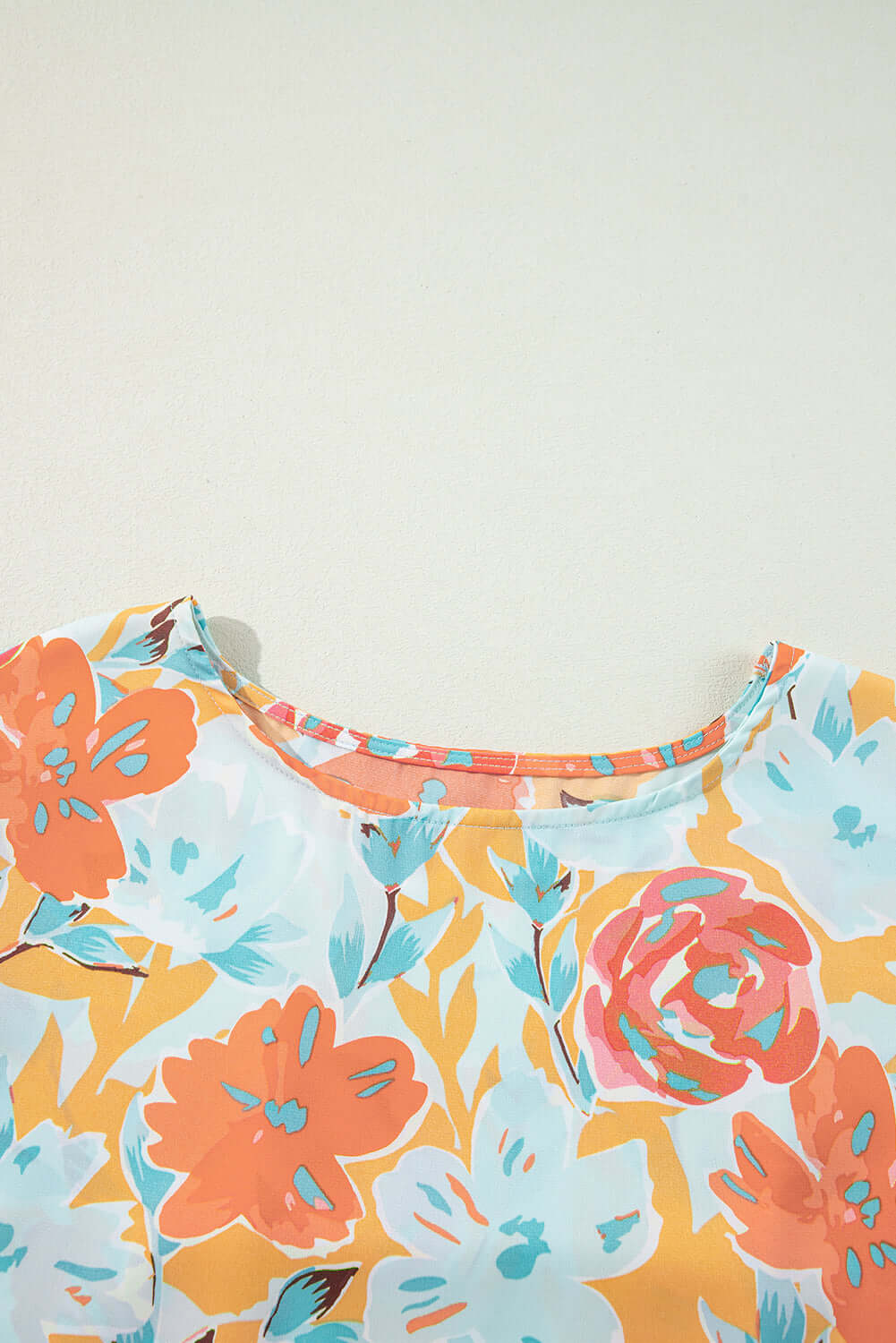 Close-up of vibrant floral print top from Sunset Stroll Pants Set, featuring tangerine, coral, and mint colors.