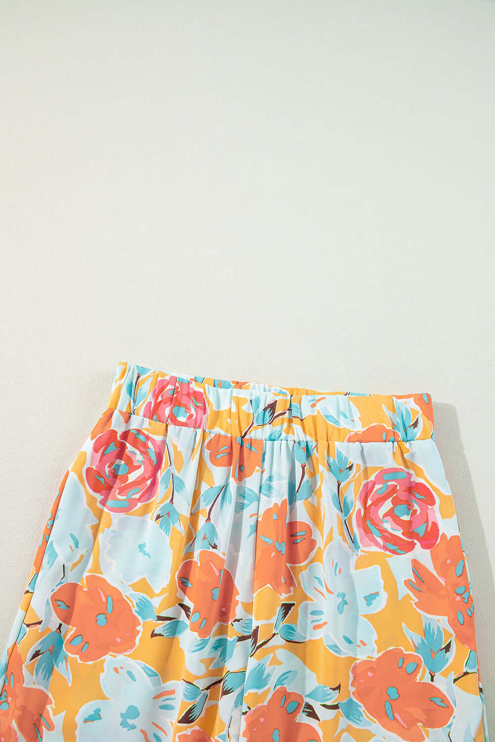 Tangerine floral print pants with oversized blooms in coral, pink, and mint. Perfect for a stylish summer look.