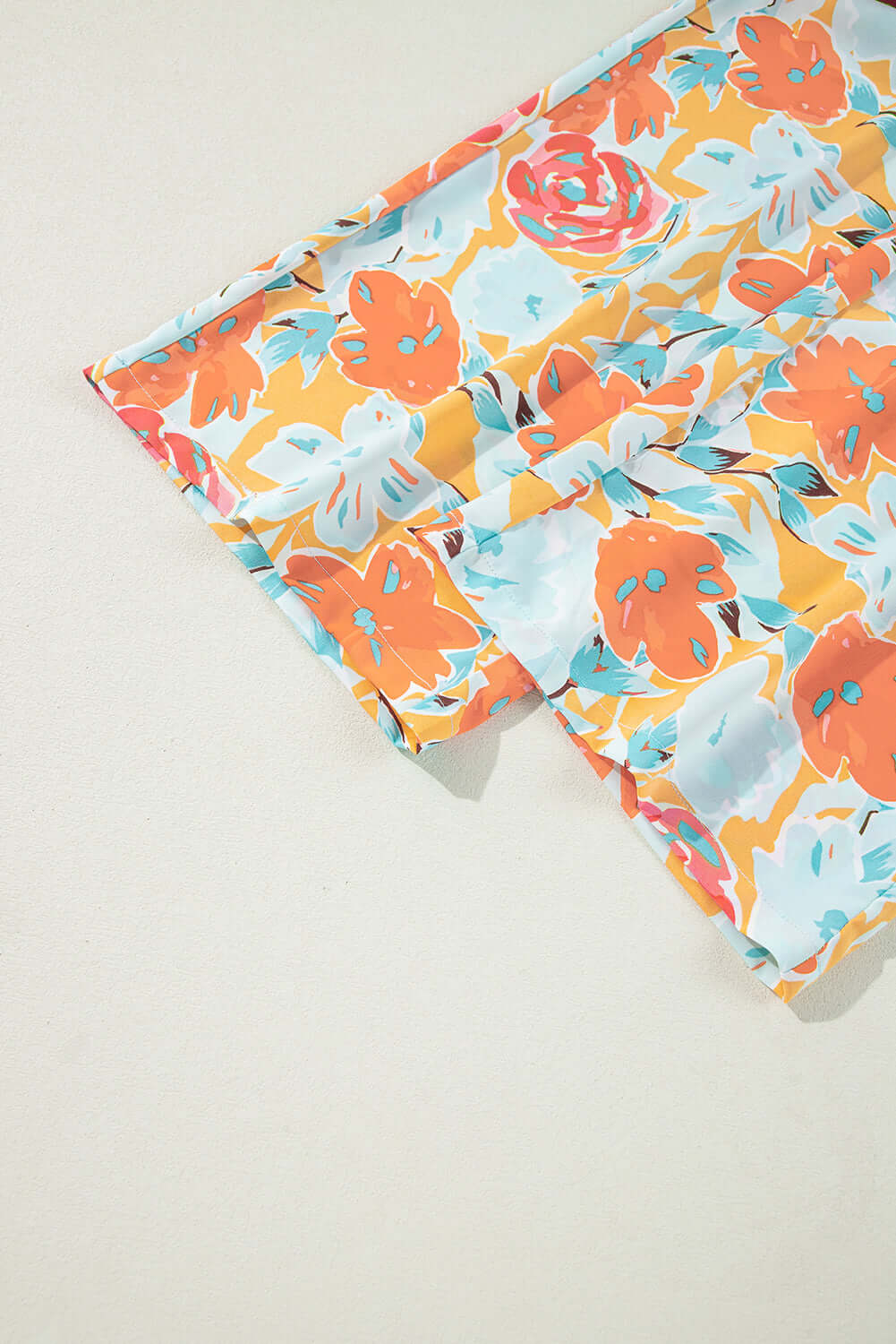 Vibrant floral fabric in tangerine and coral hues showcasing roses and blooms, perfect for sunset stroll pants set.