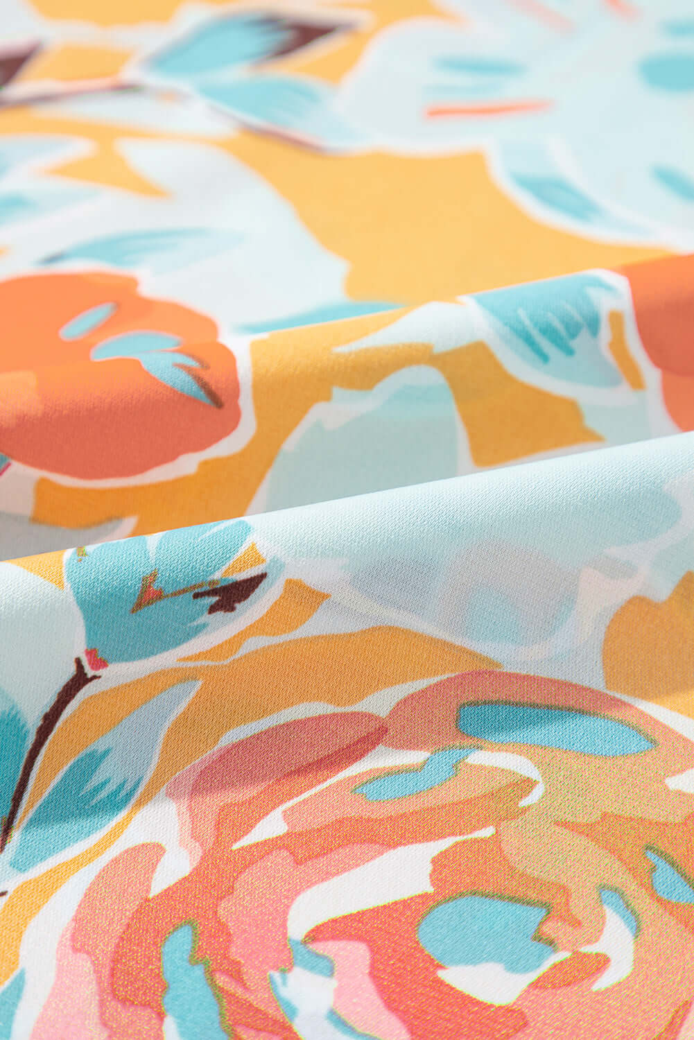 Close-up of vibrant floral fabric featuring tangerine, coral, pink, and mint colors for the Sunset Stroll Pants Set.