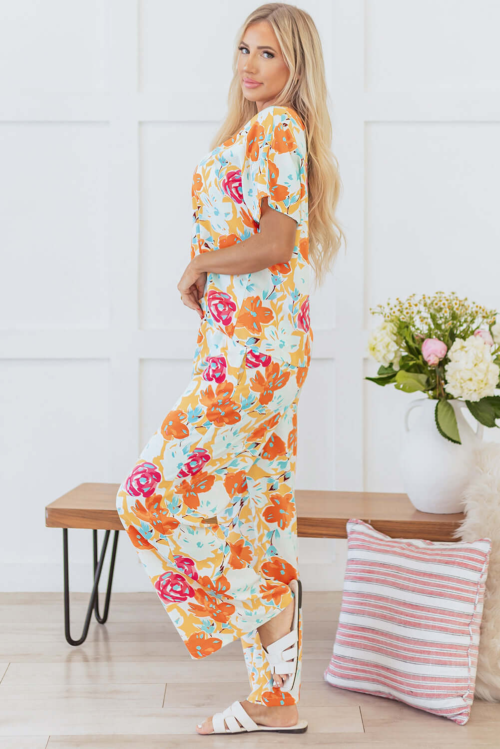 Model wearing Sunset Stroll Pants Set with vibrant floral print in tangerine, featuring a relaxed top and wide-leg pants.