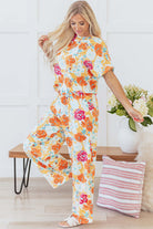 Model wearing the Sunset Stroll Pants Set, featuring a tangerine floral top and matching wide-leg pants.