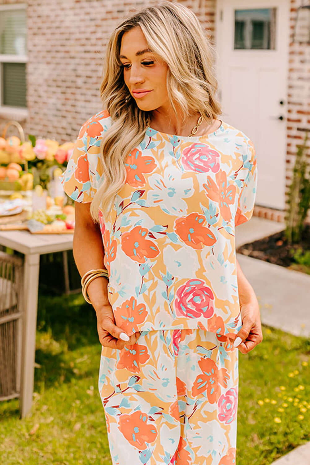 Model wearing Sunset Stroll Pants Set with vibrant floral print in tangerine, coral, pink, and mint colors.