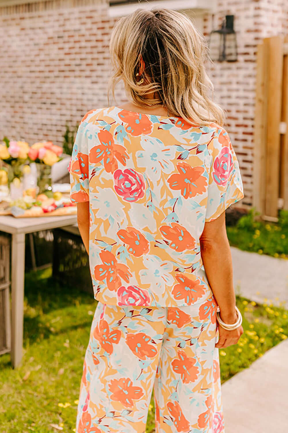 Back view of Sunset Stroll Pants Set featuring vibrant floral prints in tangerine, coral, and pink for a stylish summer look.