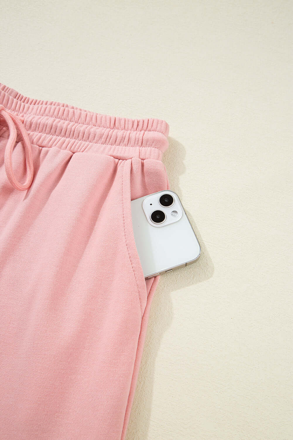 Pink cargo sweatpants pocket with a smartphone, showcasing style and functionality in casual wear.