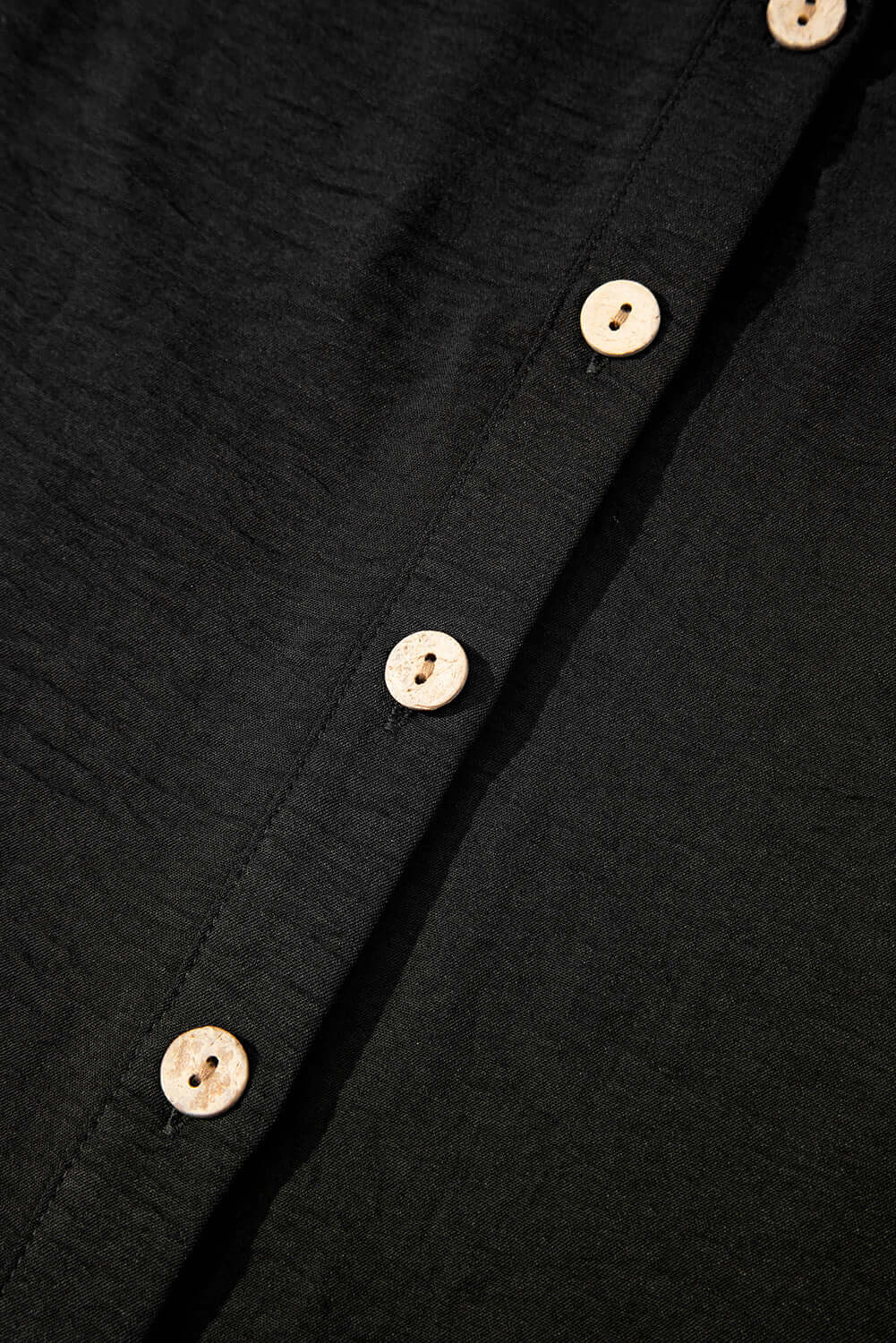 Close-up of black fabric with wooden buttons, showcasing the buttoned vest from the Oasis Moment 2 Piece Pants Set.