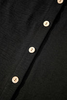 Close-up of black fabric with wooden buttons, showcasing the buttoned vest from the Oasis Moment 2 Piece Pants Set.