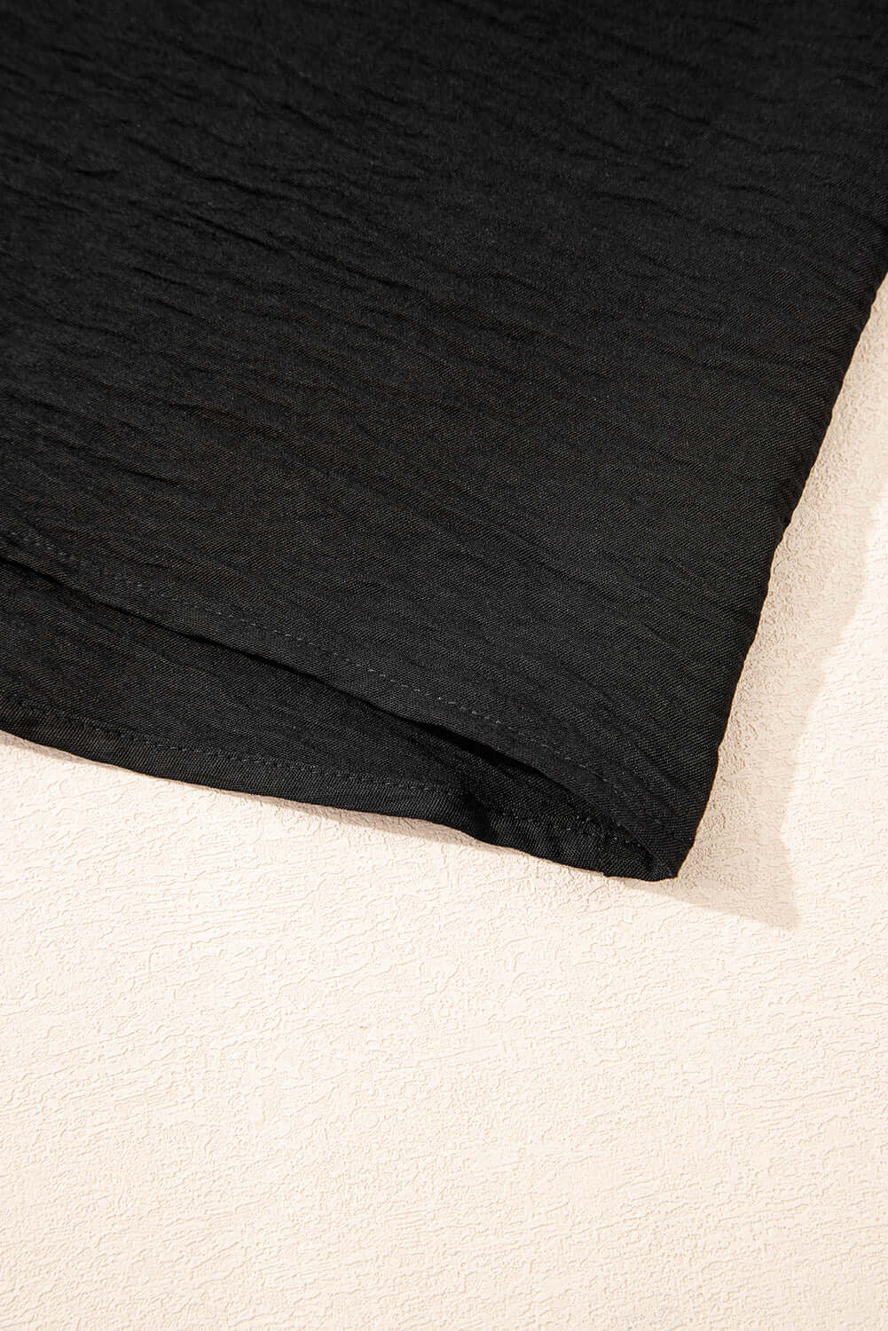 Close-up of the hem of the black Oasis Moment 2 Piece Pants Set, showcasing its textured fabric and relaxed design.