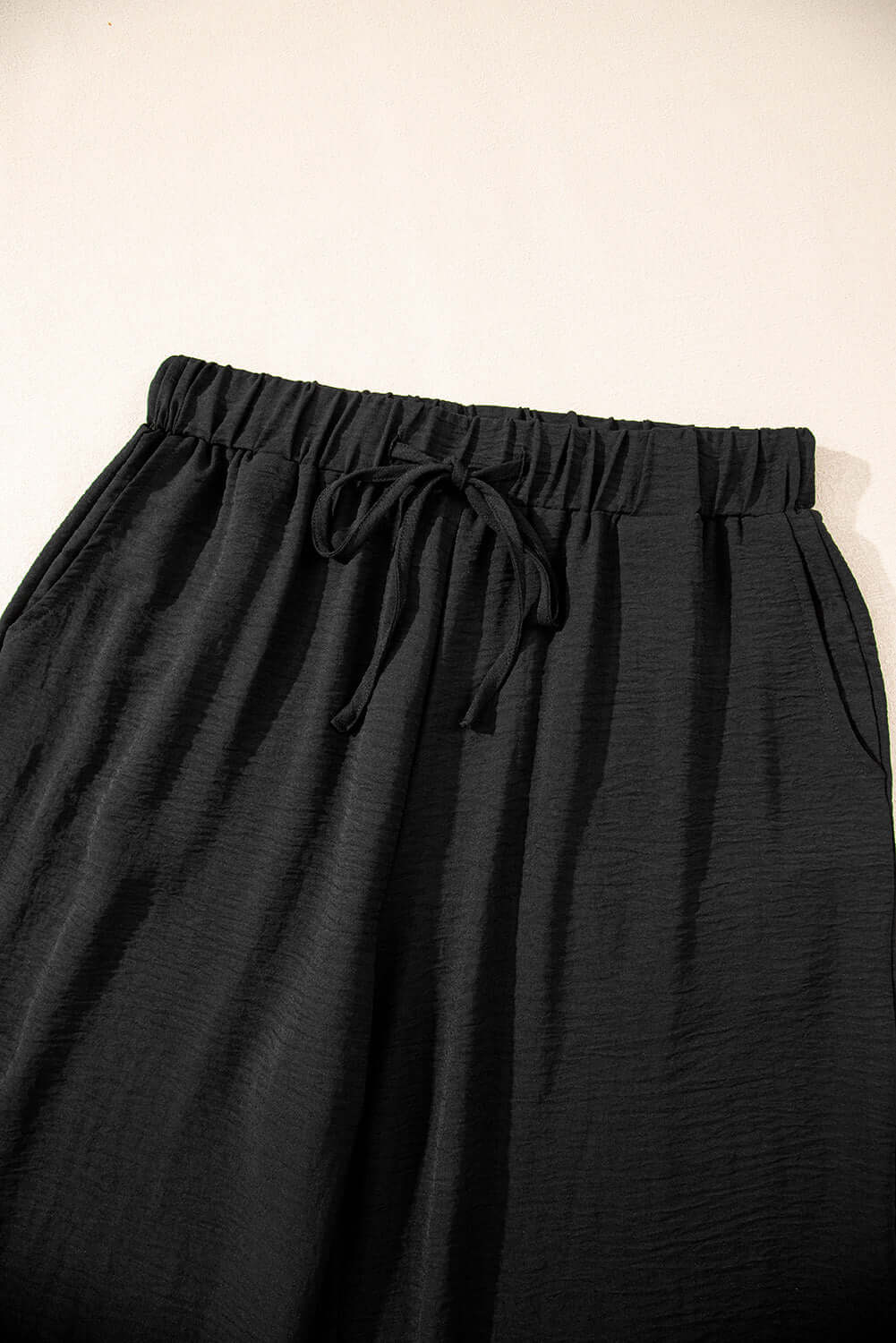 Close-up of black drawstring wide-leg pants from the Oasis Moment 2-piece set, showcasing soft fabric and relaxed fit.