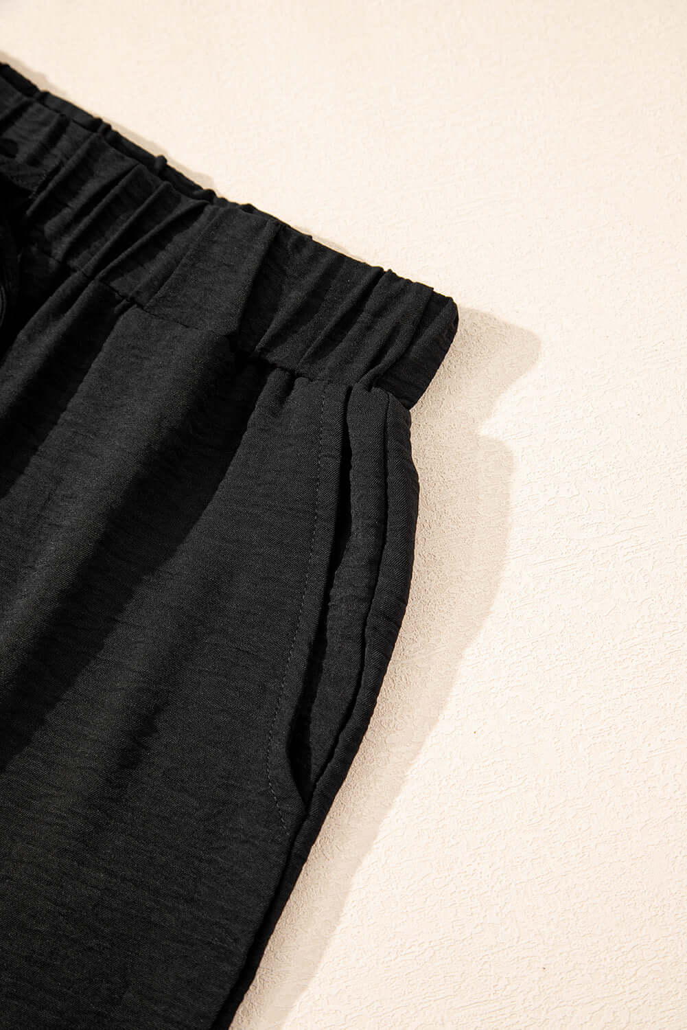 Close-up of black wide-leg pants with elastic waistband and relaxed fit, showcasing elegant style and comfort.