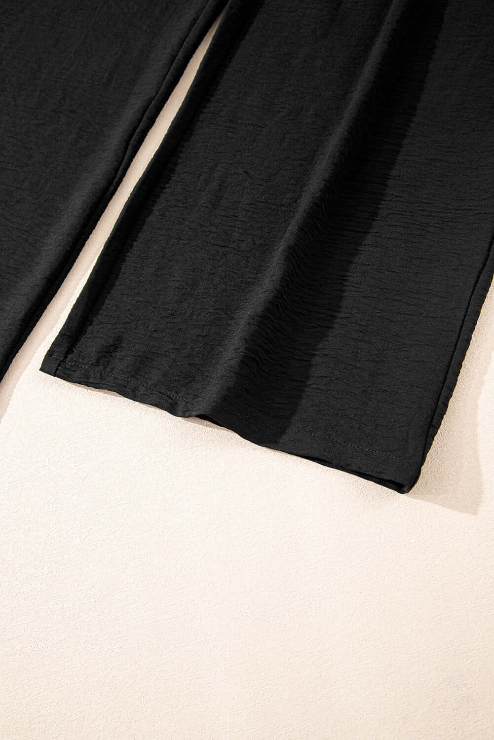 Close-up of black wide-leg pants from the Oasis Moment 2 Piece Pants Set on a light background.