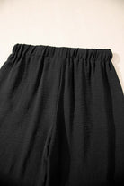 Close-up of the elastic waistband of black wide-leg pants from the Oasis Moment 2 Piece Set.