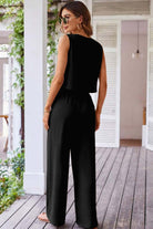 Chic black 2-piece pants set featuring a buttoned crop vest and wide-leg pants, showcased in an elegant outdoor setting.