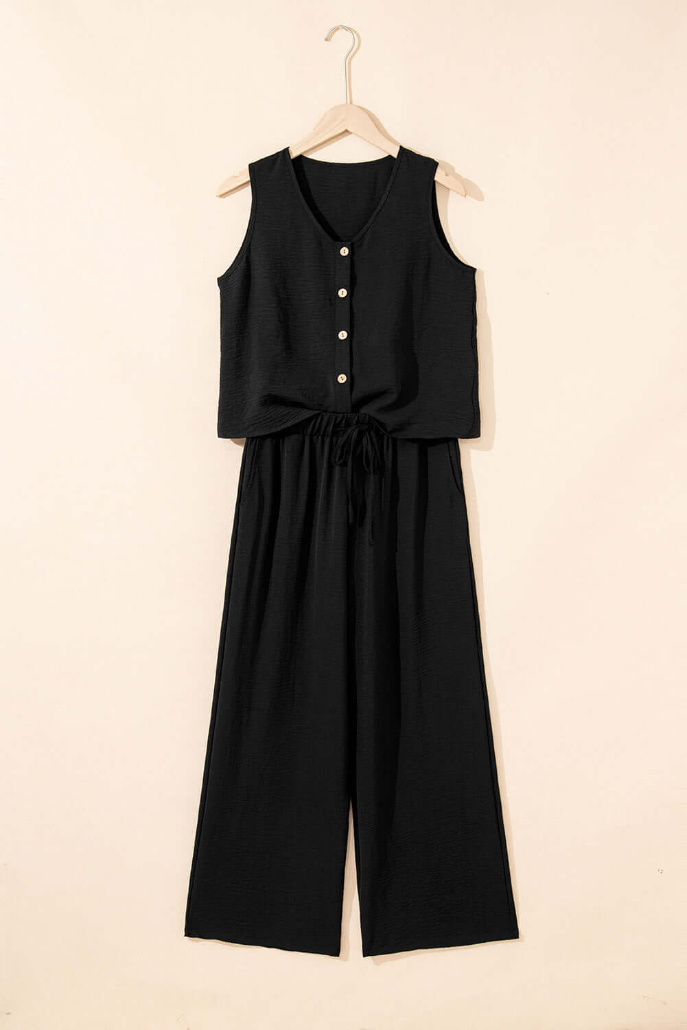 Oasis Moment black 2-piece set featuring a buttoned crop vest and wide-leg pants hung on a hanger.