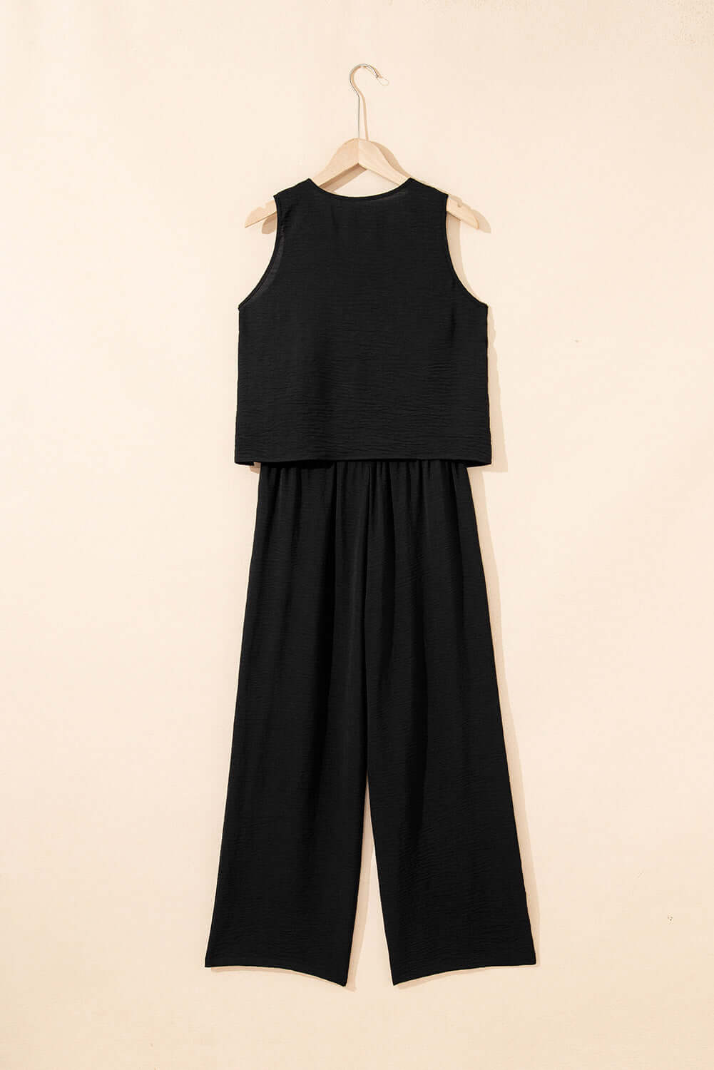 Oasis Moment 2 Piece Pants Set in black featuring a buttoned vest and wide-leg pants, styled elegantly on a hanger.