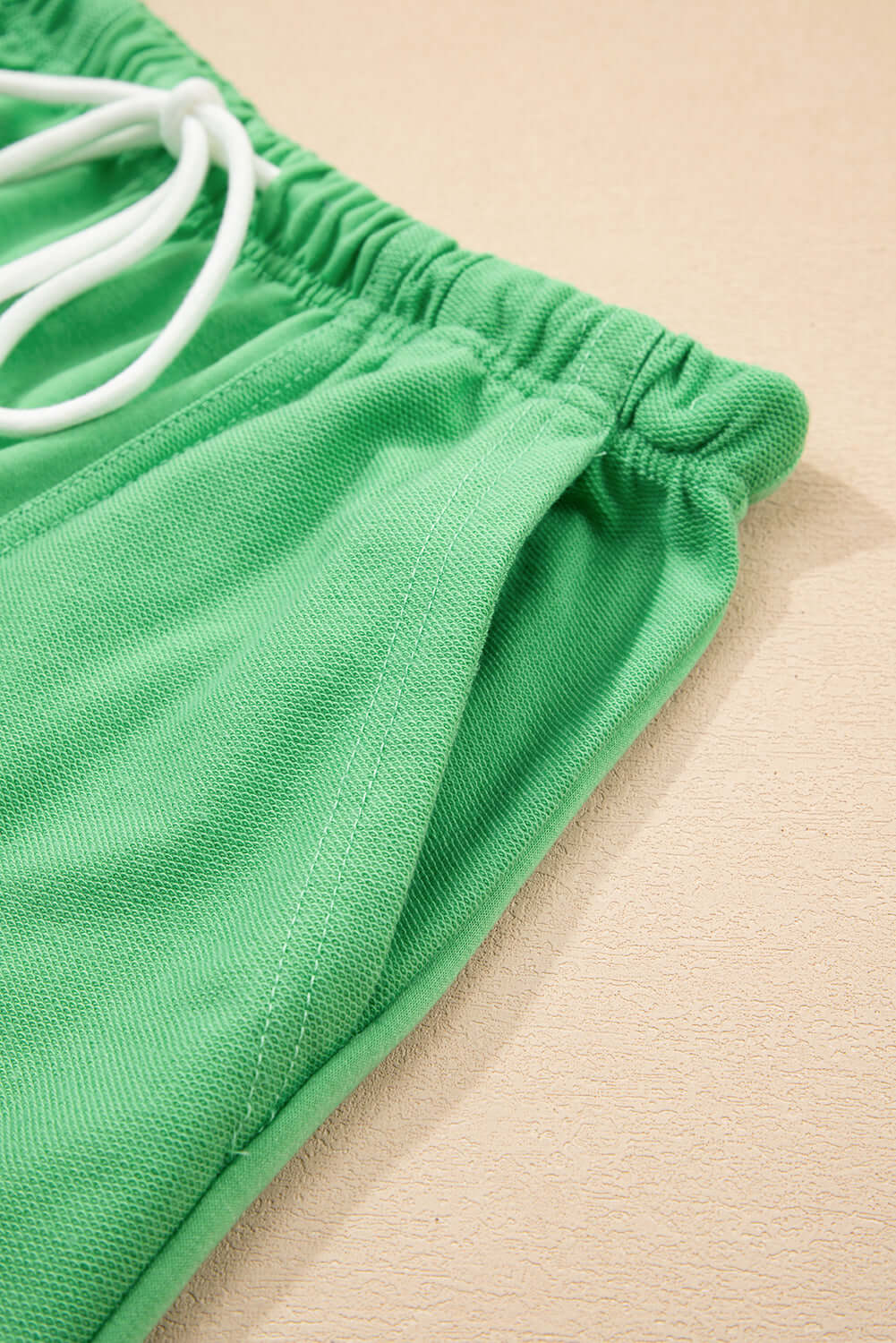 Close-up of bright green shorts showing adjustable drawstring and elastic waistline for comfort.