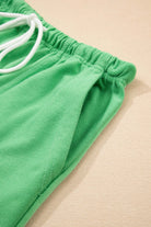Close-up of bright green shorts showing adjustable drawstring and elastic waistline for comfort.