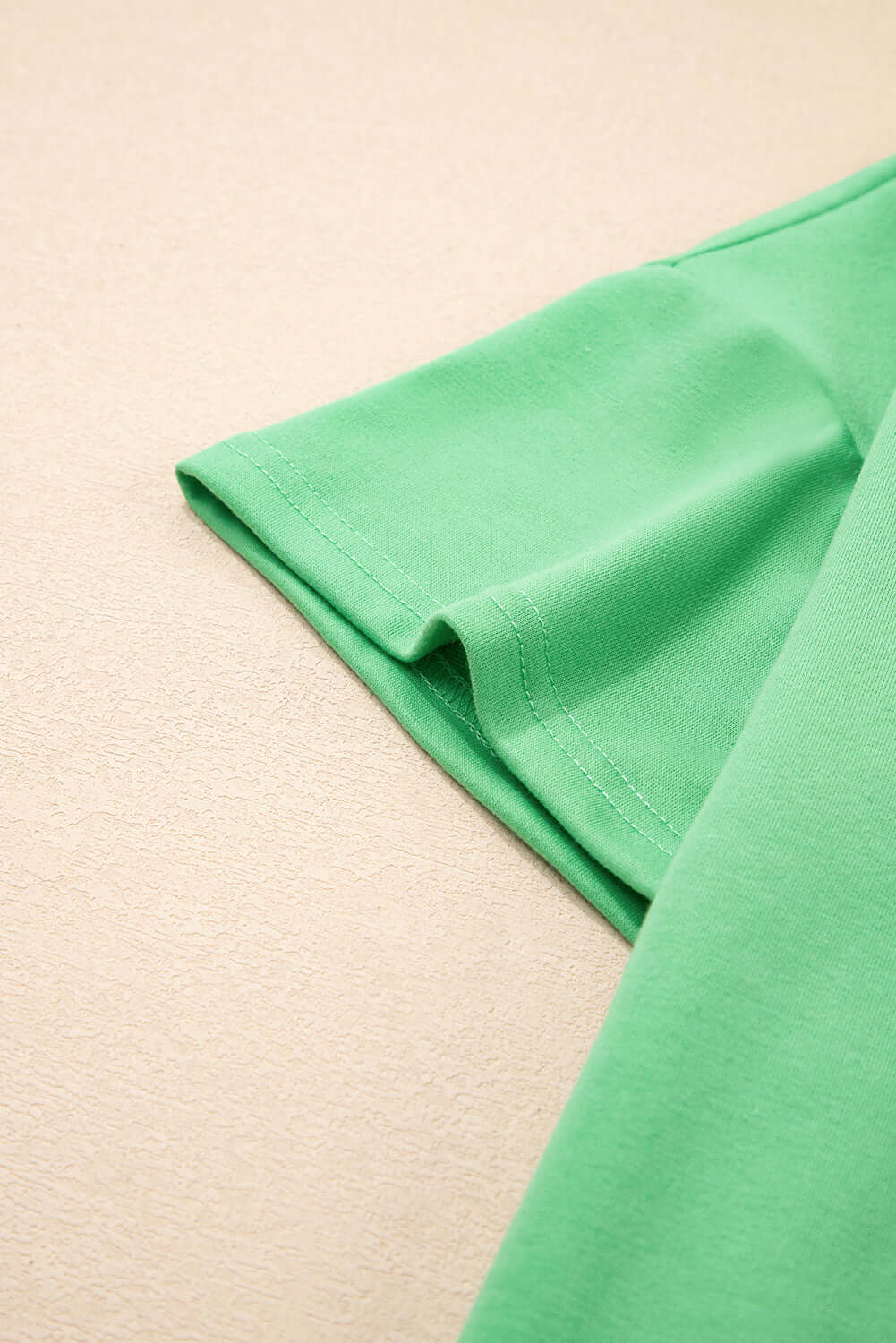 Close-up of Zest for Life bright green V-neck tee sleeve, highlighting relaxed fit and drop shoulder design.