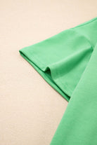 Close-up of Zest for Life bright green V-neck tee sleeve, highlighting relaxed fit and drop shoulder design.